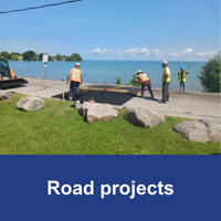 four construction workers working on a speed hump with blue bar and text Road Construction