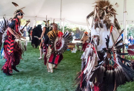 three men dressed in regalia dancing to drums